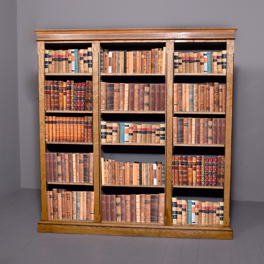 A large Victorian Arts and Crafts open bookcase crafted from warm brown elm featuring three vertical sections with decorative inlaid borders.