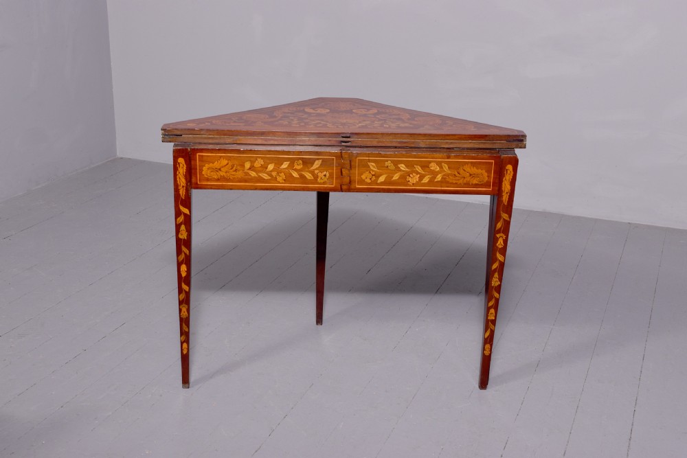 A triangular wooden Dutch card table featuring detailed floral marquetry inlay on the top surface and tapered square legs. View V