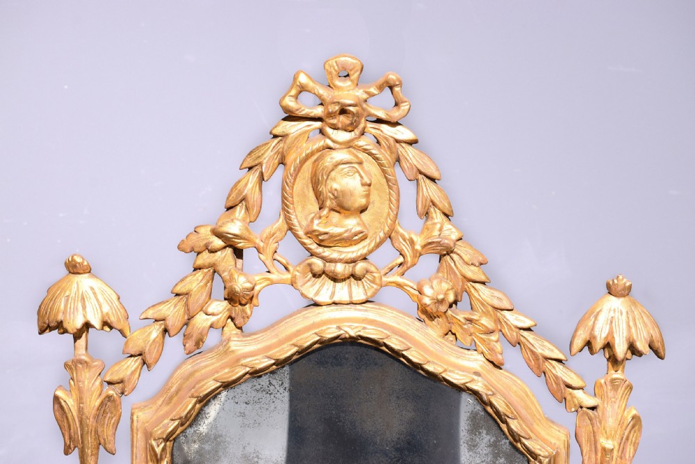 A late 18th-century Neoclassical giltwood wall mirror with a carved ribbon crest, profile medallion, and side foliate columns. View III