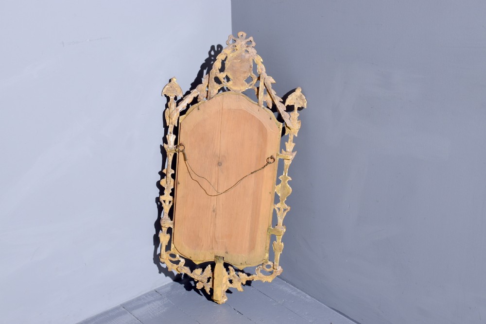 A late 18th-century Neoclassical giltwood wall mirror with a carved ribbon crest, profile medallion, and side foliate columns. View V
