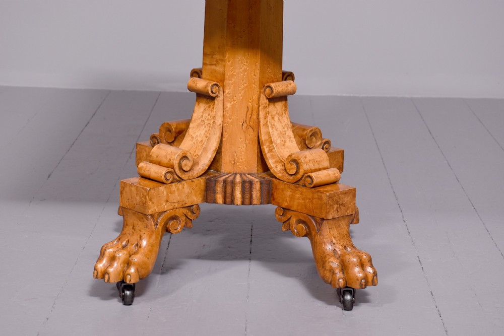 A George IV birdseye maple fold-over tea table featuring rosewood crossbanding, a central pedestal, and carved lion paw feet on brass castors. View IV