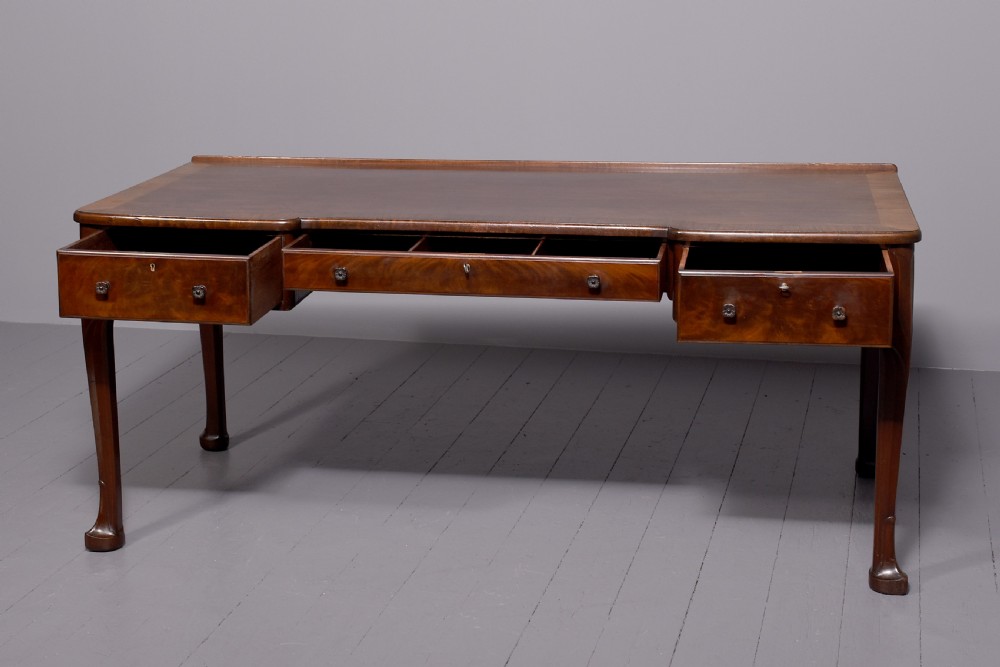 A large crossbanded mahogany library desk featuring three frieze drawers and slender cabriole legs. View VI