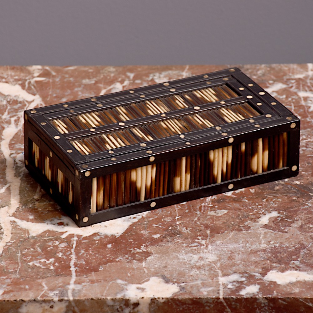 An Edwardian rectangular porcupine quill box with dark ebonised wooden framing and circular bone dot inlays.
