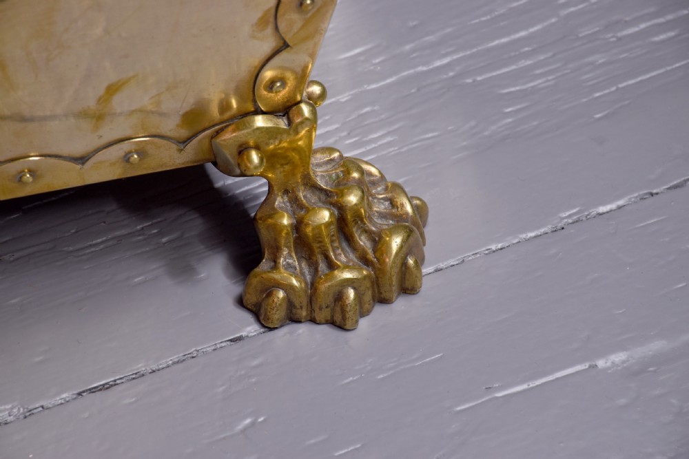 A rectangular Victorian brass coal bucket featuring scalloped edges, side handles, a central lion mask motif, and four cast paw feet. View II