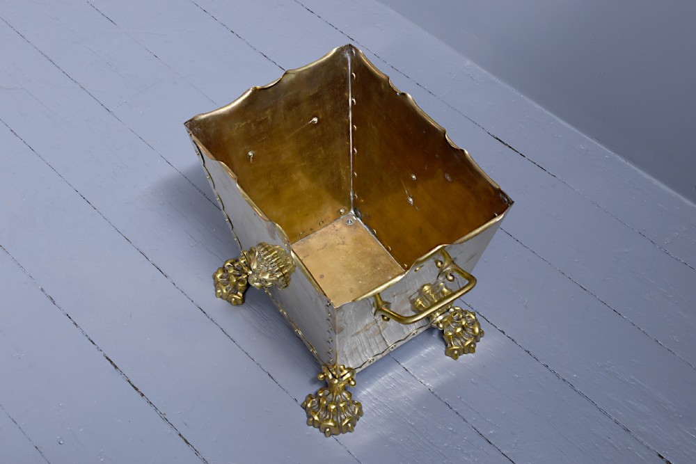 A rectangular Victorian brass coal bucket featuring scalloped edges, side handles, a central lion mask motif, and four cast paw feet. View III