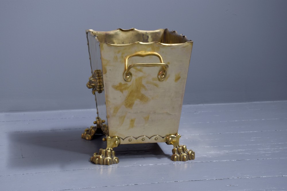 A rectangular Victorian brass coal bucket featuring scalloped edges, side handles, a central lion mask motif, and four cast paw feet. View IV