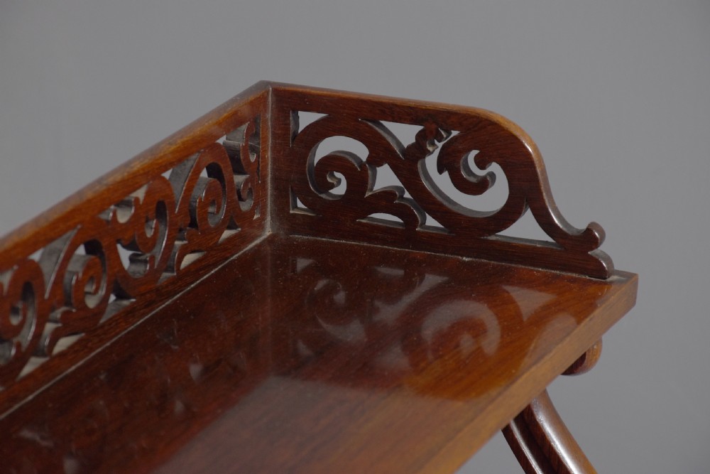 A three-tier William IV dark rosewood wall shelf featuring open shelving, curved S-scroll side supports, and a pierced fretwork top gallery rail. View IV