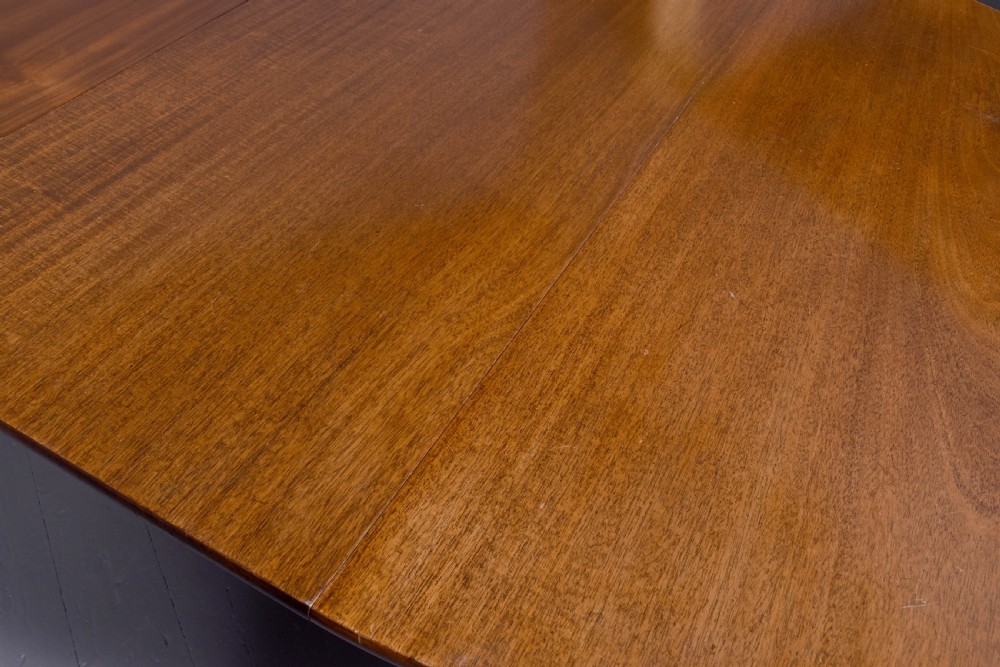 An oval antique timber extending dining table with tapered legs and sculpted pad feet. View II