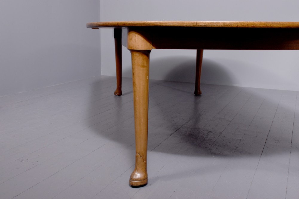 An oval antique timber extending dining table with tapered legs and sculpted pad feet. View IV