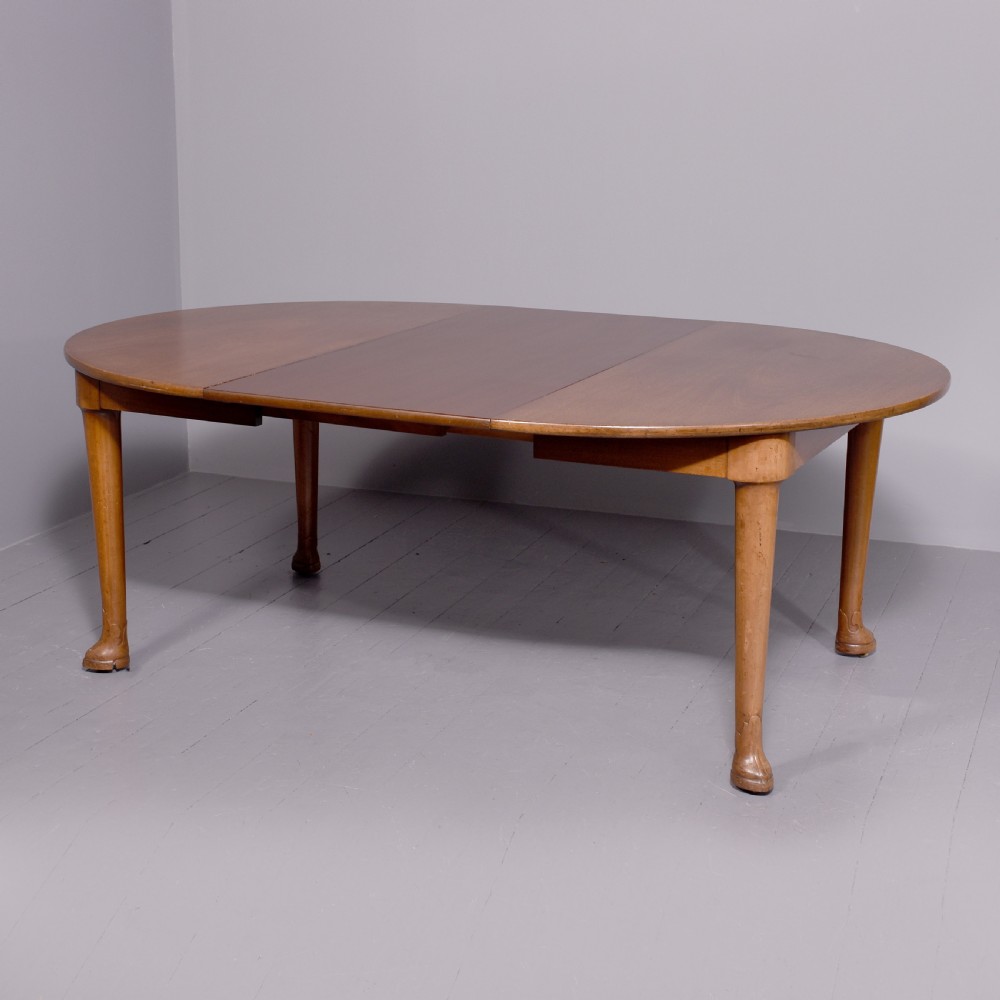 An oval antique timber extending dining table with tapered legs and sculpted pad feet. View VI