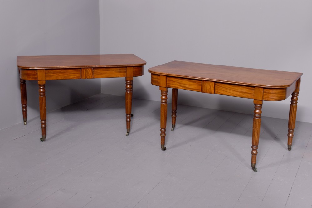 An extendable George IV mahogany dining table featuring a rectangular top with rounded corners, resting on four reeded turned legs with brass castors. View VII
