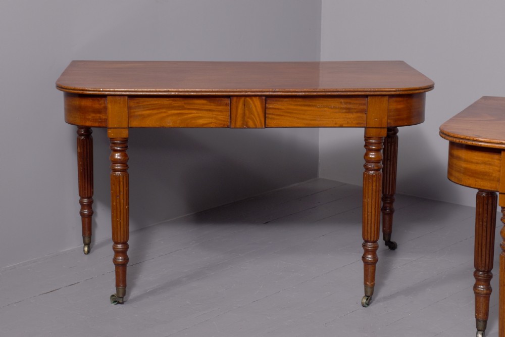 An extendable George IV mahogany dining table featuring a rectangular top with rounded corners, resting on four reeded turned legs with brass castors. View VIII