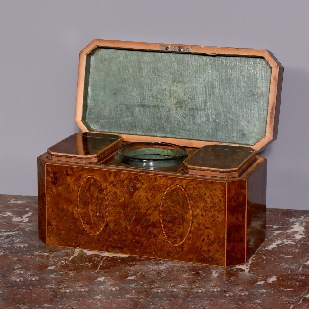 An 18th-century George III wooden tea caddy with a burr veneer finish, oval stringing inlays, canted corners, and a top brass handle. View II