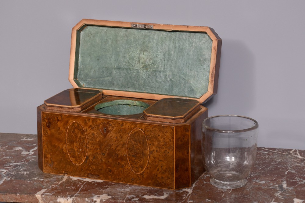 An 18th-century George III wooden tea caddy with a burr veneer finish, oval stringing inlays, canted corners, and a top brass handle. View III