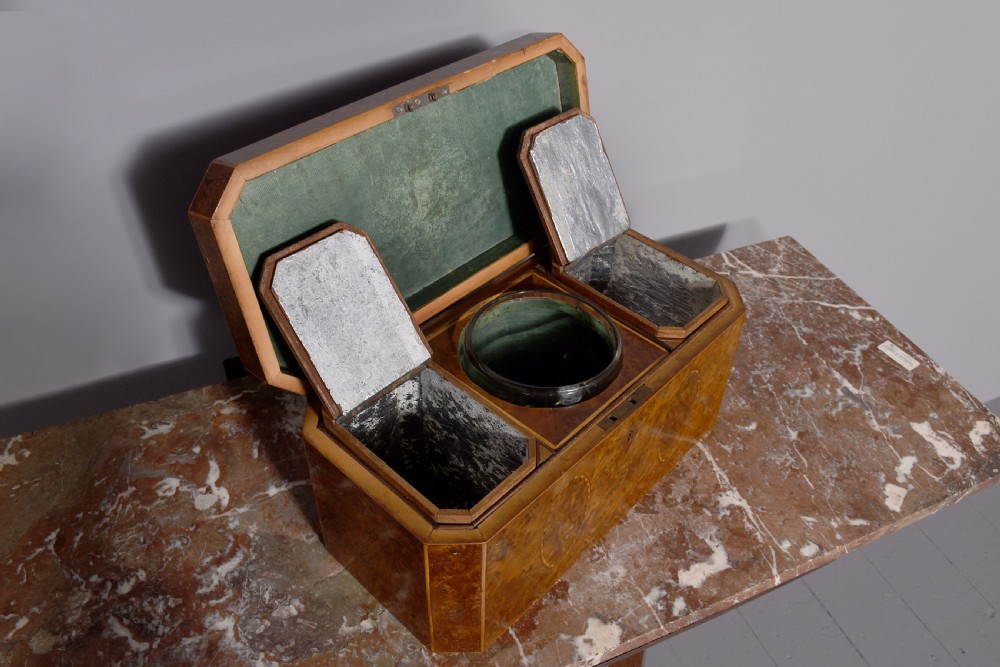 An 18th-century George III wooden tea caddy with a burr veneer finish, oval stringing inlays, canted corners, and a top brass handle. View IV
