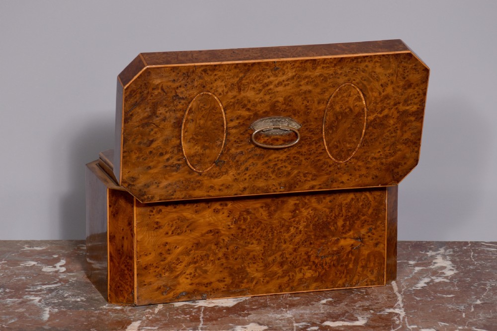An 18th-century George III wooden tea caddy with a burr veneer finish, oval stringing inlays, canted corners, and a top brass handle. View V