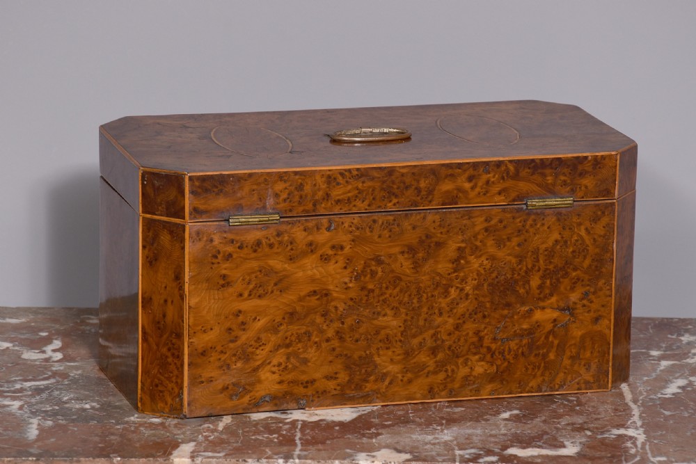 An 18th-century George III wooden tea caddy with a burr veneer finish, oval stringing inlays, canted corners, and a top brass handle. View VI