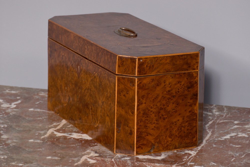 An 18th-century George III wooden tea caddy with a burr veneer finish, oval stringing inlays, canted corners, and a top brass handle. View VII