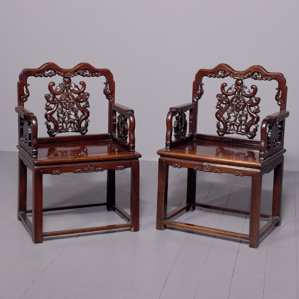 A pair of dark polished hardwood Chinese Qing Dynasty throne chairs featuring intricate openwork carved back splats with longevity symbols and carved armrests.