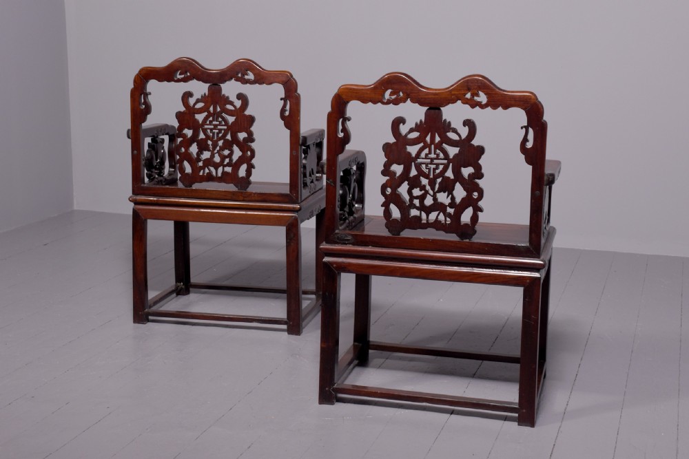 A pair of dark polished hardwood Chinese Qing Dynasty throne chairs featuring intricate openwork carved back splats with longevity symbols and carved armrests. View V