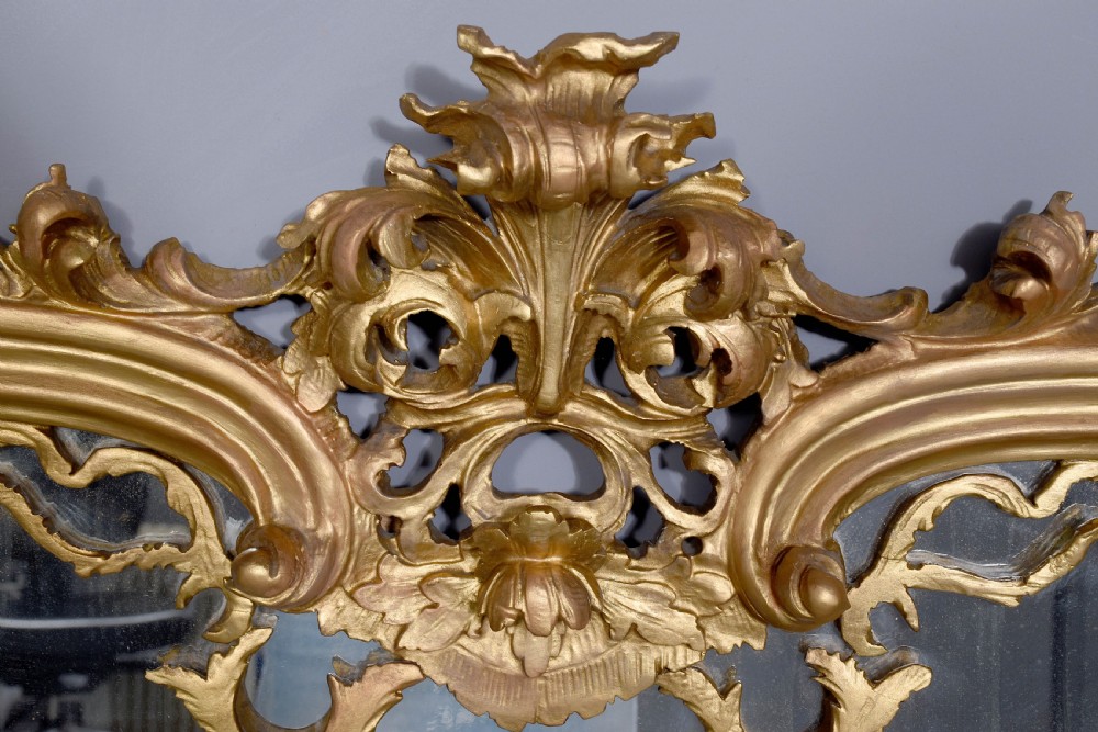 A wide carved giltwood overmantel mirror featuring ornate Rococo scrollwork, acanthus leaf motifs, and an arched cresting. View VI