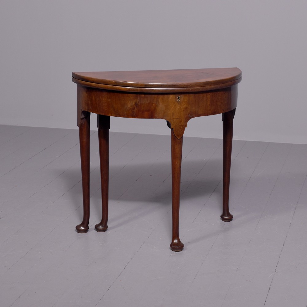 An 18th-century George III mahogany D-shaped card table with cabriole legs and pad feet shown in a folded configuration.