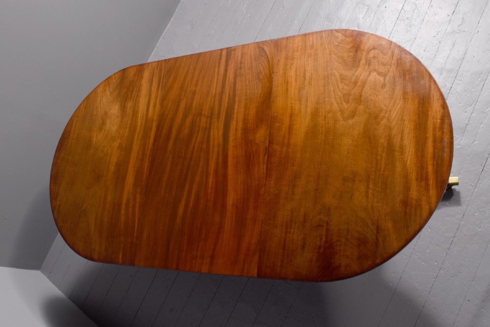 A mahogany twin pillar dining table featuring reeded splayed legs with brass castors and a polished wood finish. View II