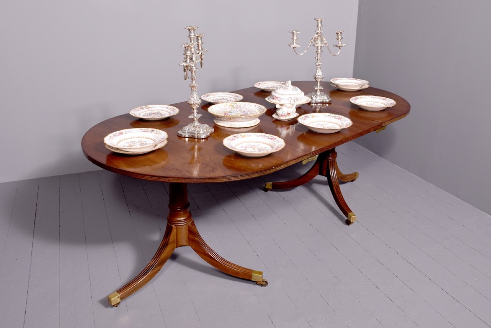 A mahogany twin pillar dining table featuring reeded splayed legs with brass castors and a polished wood finish. View III