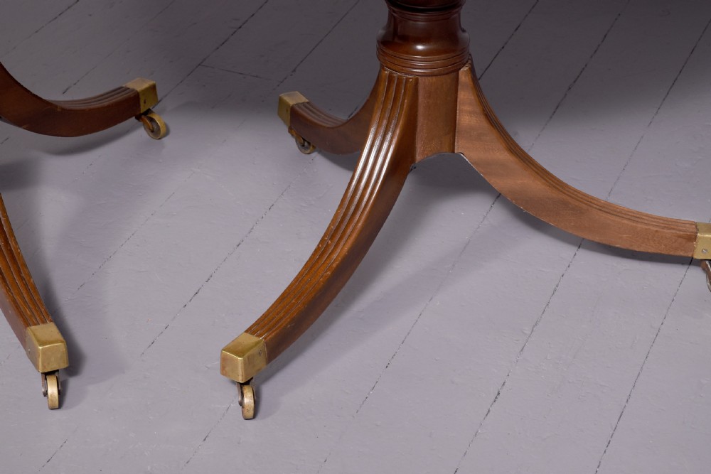 A mahogany twin pillar dining table featuring reeded splayed legs with brass castors and a polished wood finish. View VIII