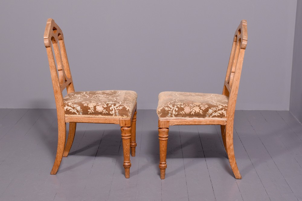 A pair of light oak side chairs featuring Gothic arched cut-outs on the backrests, turned front legs, and patterned gold velvet upholstery. View II