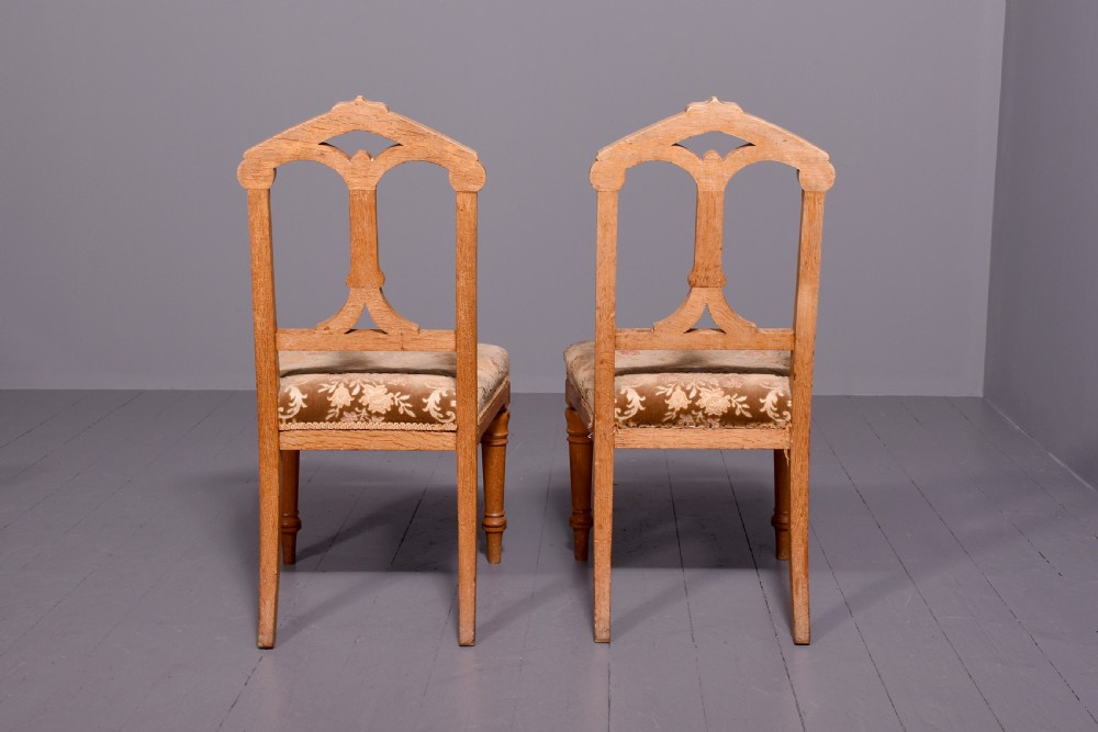 A pair of light oak side chairs featuring Gothic arched cut-outs on the backrests, turned front legs, and patterned gold velvet upholstery. View III