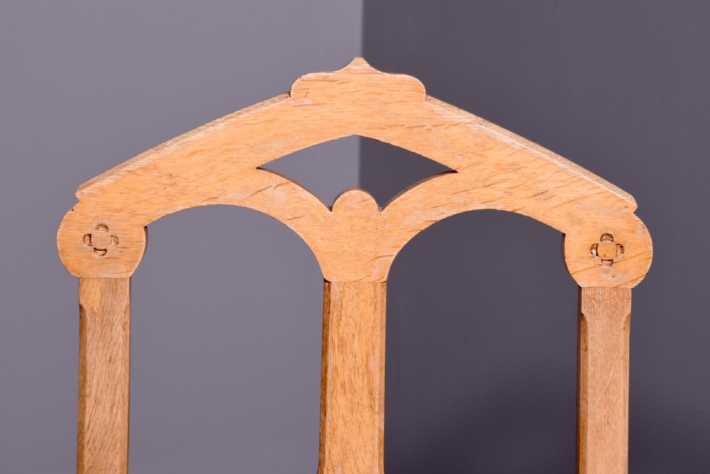 A pair of light oak side chairs featuring Gothic arched cut-outs on the backrests, turned front legs, and patterned gold velvet upholstery. View V
