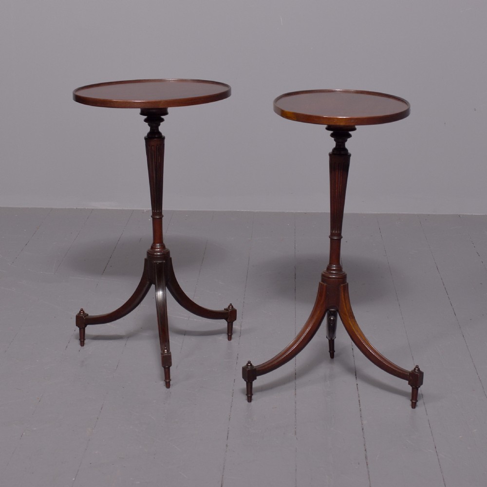 A pair of Regency dark mahogany wine tables featuring circular dish tops, fluted tapered stems, and swept tripod legs.