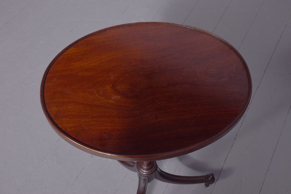 A pair of Regency dark mahogany wine tables featuring circular dish tops, fluted tapered stems, and swept tripod legs. View II