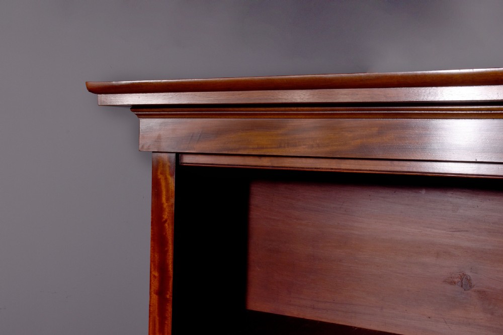 A large mid-Victorian mahogany bookcase featuring a three-bay open upper section with adjustable shelves set above a three-door cupboard base with oval veneered panels. View X