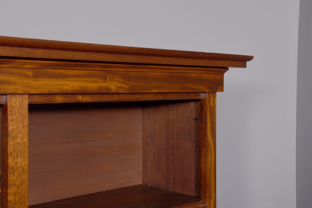 A large mid-Victorian mahogany bookcase featuring a three-bay open upper section with adjustable shelves set above a three-door cupboard base with oval veneered panels. View XI