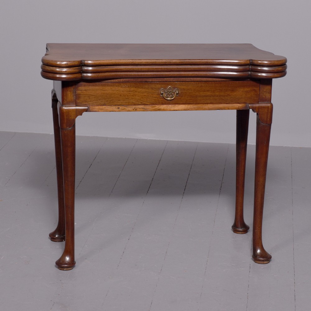 A George III mahogany triple top games table featuring cabriole legs ending in pad feet and a single frieze drawer with a brass handle.