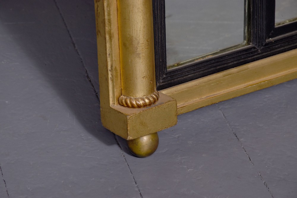 A horizontal Regency giltwood triptych overmantel mirror featuring acanthus leaf columns, a breakfront cornice, and three mirror plates framed with ebonised inner slip. View II
