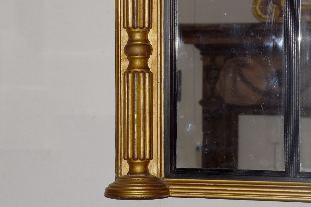 A horizontal Regency giltwood triptych overmantel mirror featuring three mirror plates flanked by fluted columns and topped with a beaded cornice. View II