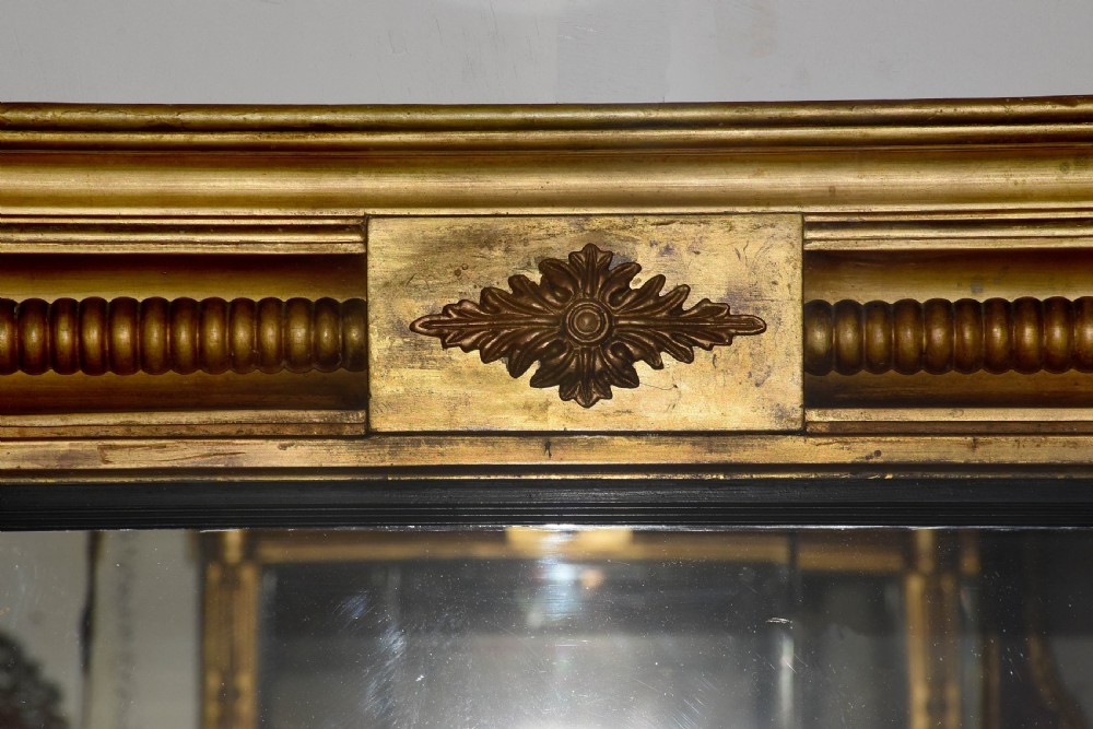 A horizontal Regency giltwood triptych overmantel mirror featuring three mirror plates flanked by fluted columns and topped with a beaded cornice. View V