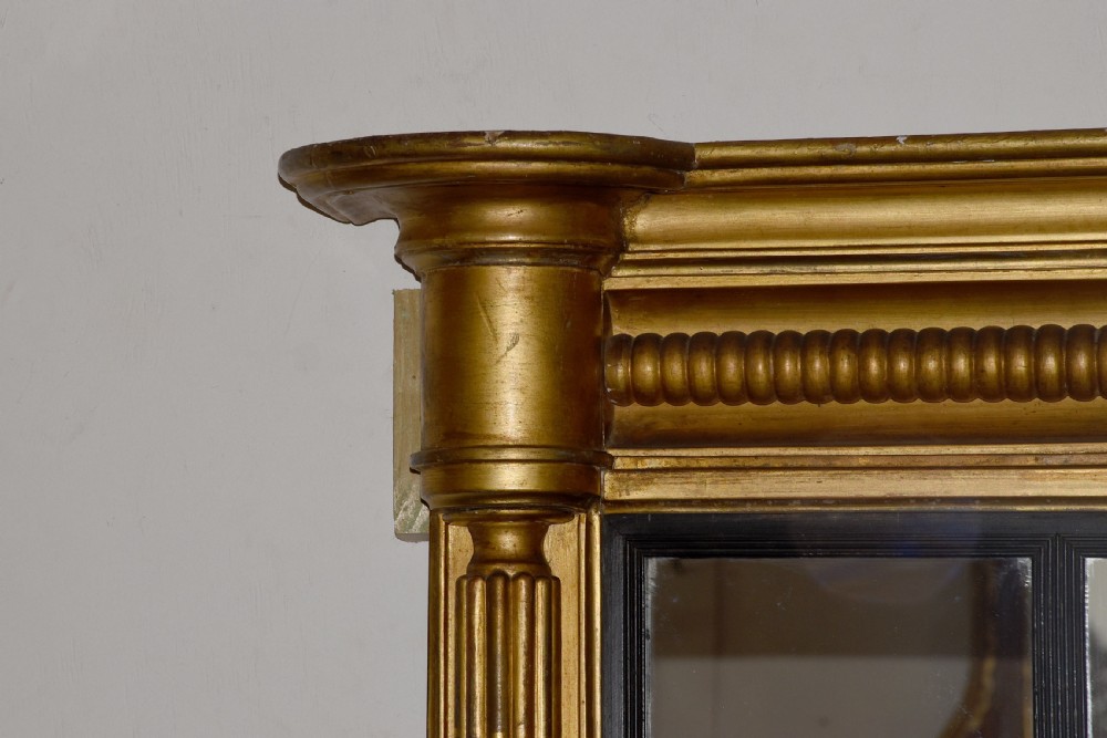 A horizontal Regency giltwood triptych overmantel mirror featuring three mirror plates flanked by fluted columns and topped with a beaded cornice. View VI