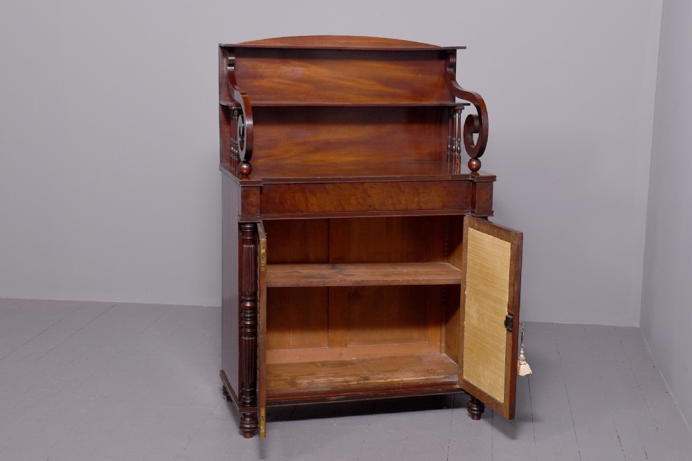 A dark mahogany Regency chiffonier featuring an upper open shelf supported by scrolled sides and two lower cupboard doors with diamond brass grilles. View VIII