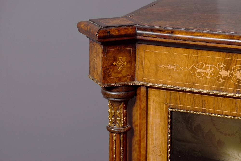 A mid-Victorian burr walnut credenza featuring a central panel door with floral marquetry inlay, flanked by two glazed display doors housing fabric-lined shelves. View II