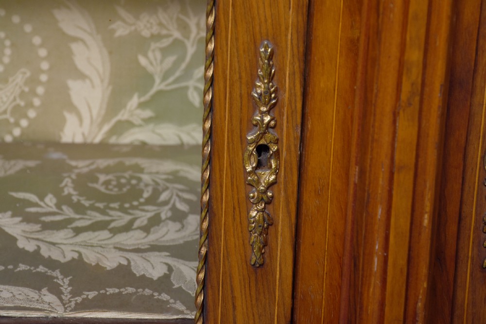 A mid-Victorian burr walnut credenza featuring a central panel door with floral marquetry inlay, flanked by two glazed display doors housing fabric-lined shelves. View V