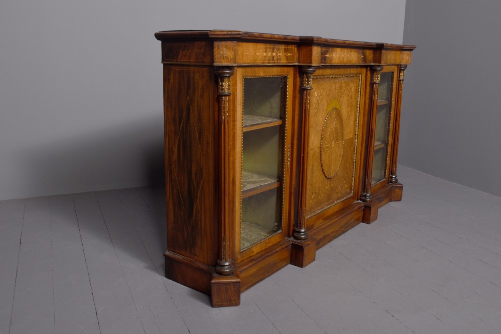 A mid-Victorian burr walnut credenza featuring a central panel door with floral marquetry inlay, flanked by two glazed display doors housing fabric-lined shelves. View VIII