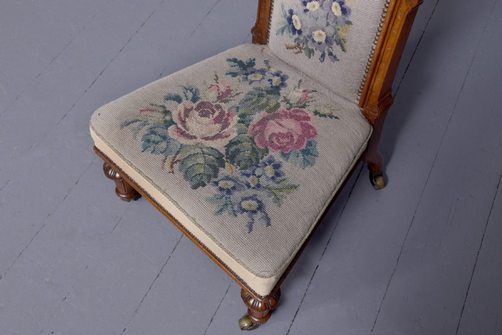 A Victorian prie-dieu chair featuring floral needlepoint upholstery on a carved wood frame with turned front legs and brass castors. View IV