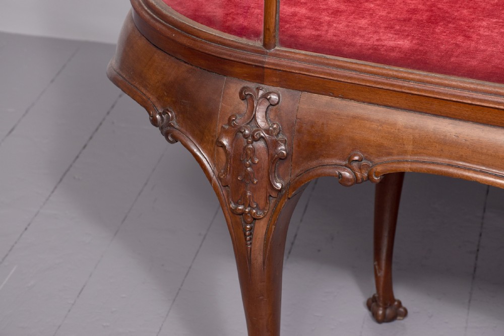 A large oval mahogany display cabinet featuring curved glass sides, red velvet lining, carved cabriole legs, and claw and ball feet. View II