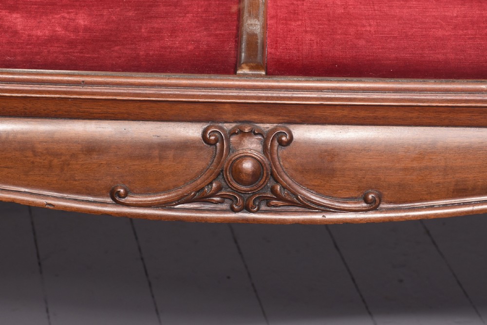 A large oval mahogany display cabinet featuring curved glass sides, red velvet lining, carved cabriole legs, and claw and ball feet. View III