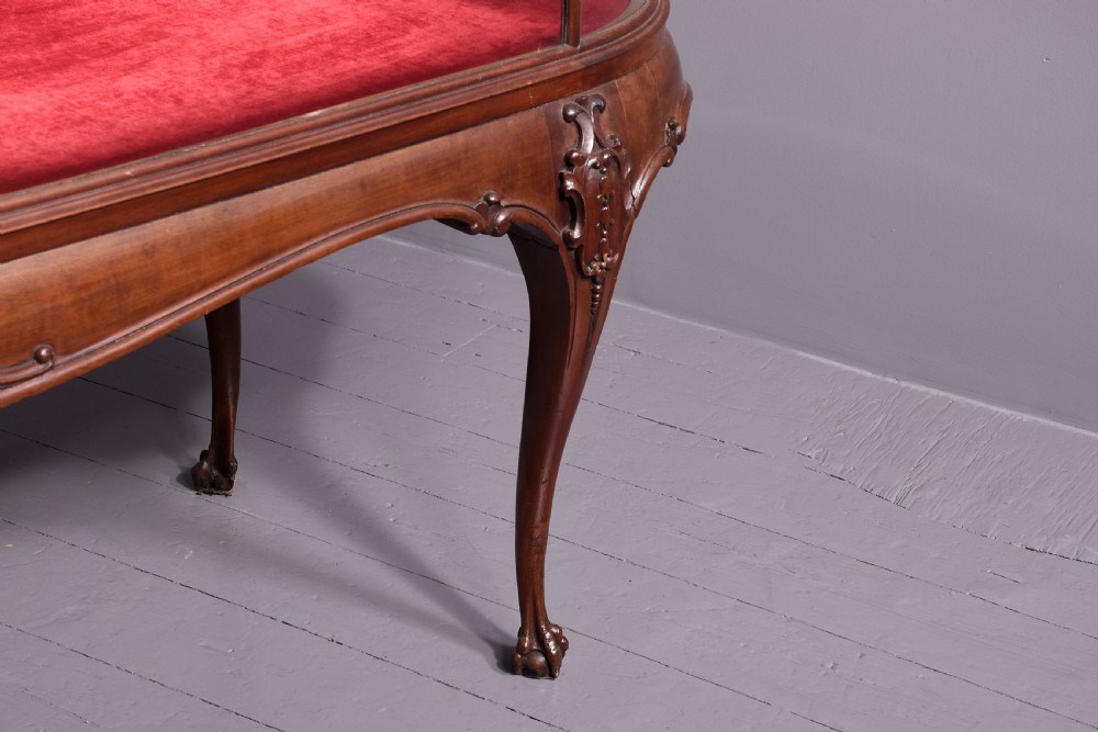 A large oval mahogany display cabinet featuring curved glass sides, red velvet lining, carved cabriole legs, and claw and ball feet. View IV