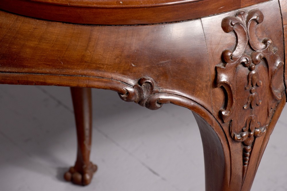 A large oval mahogany display cabinet featuring curved glass sides, red velvet lining, carved cabriole legs, and claw and ball feet. View V